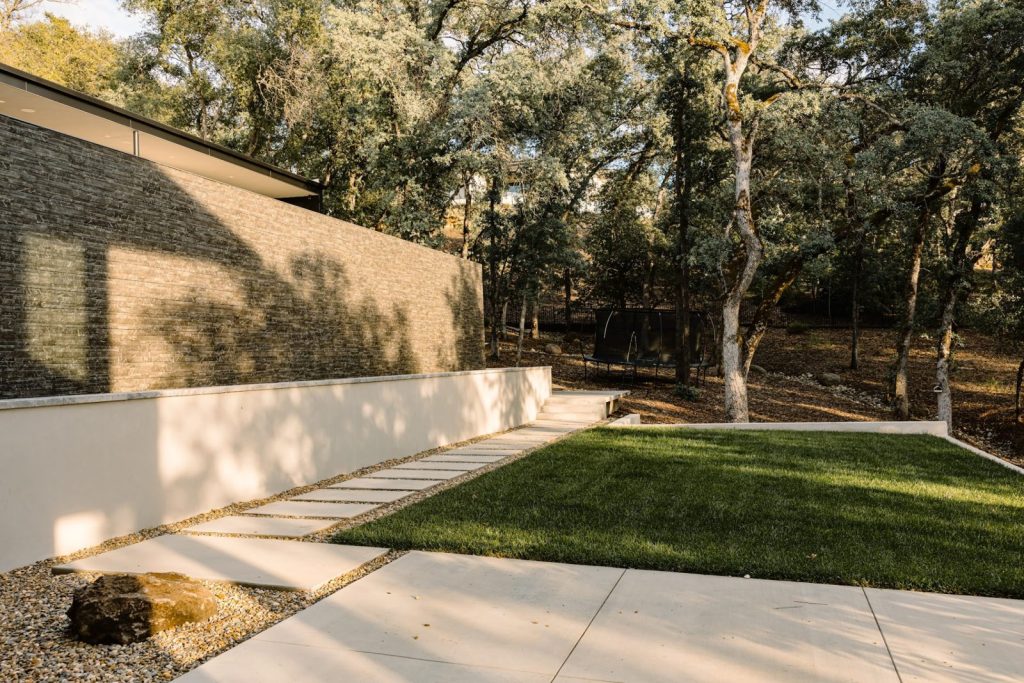 Concrete retaining wall beside a backyard lawn and walkway